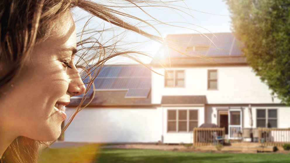 Frauengesicht vor Wohnhaus mit Solaranlage